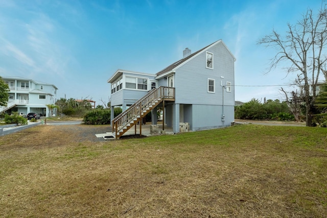 back of house with a chimney, stairway, and a yard