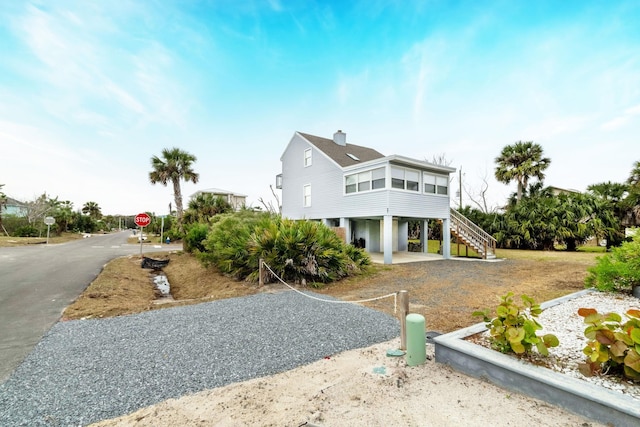 back of property featuring a carport, stairway, and driveway