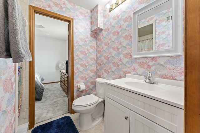 bathroom featuring toilet, vanity, and wallpapered walls