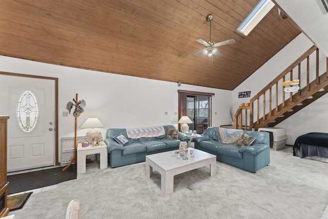 carpeted living area featuring stairs, vaulted ceiling with skylight, ceiling fan, and wood ceiling