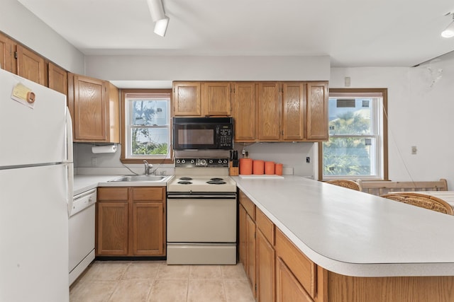 kitchen with light countertops, a healthy amount of sunlight, a sink, white appliances, and a peninsula