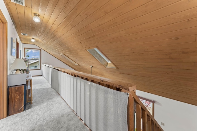 corridor featuring light carpet, visible vents, lofted ceiling with skylight, and wood ceiling