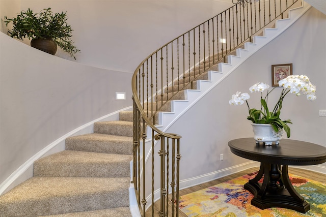 stairway featuring hardwood / wood-style flooring and a towering ceiling