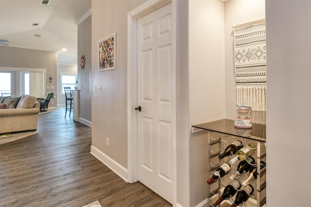 hall with dark wood-type flooring and ornamental molding