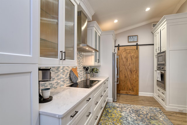 616 Mediterranean Way, Saint Augustine, FL 32080 - kitchen with stainless steel appliances, wall chimney range hood, light wood-style floors, a barn door, and crown molding