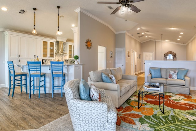 living room featuring ceiling fan, light hardwood / wood-style flooring, crown molding, and lofted ceiling