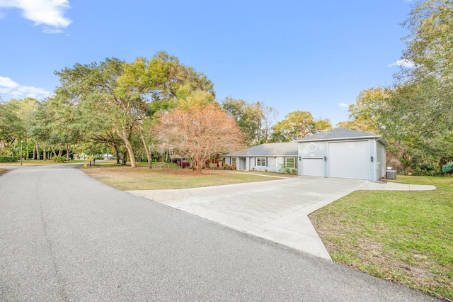 view of front of home featuring a garage, cooling unit, and a front lawn