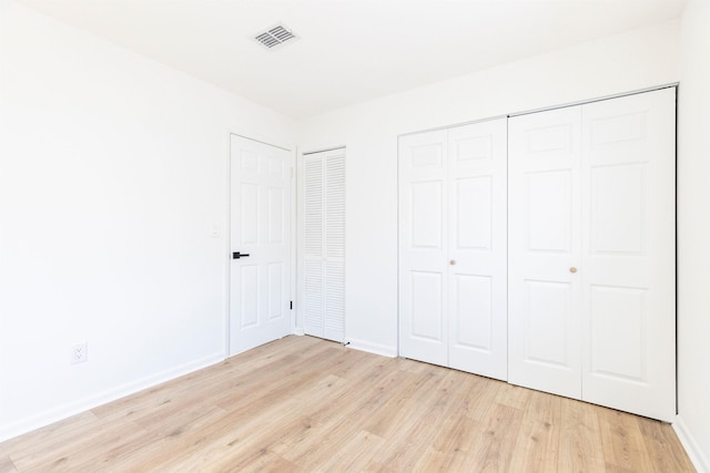 unfurnished bedroom featuring two closets and light hardwood / wood-style flooring