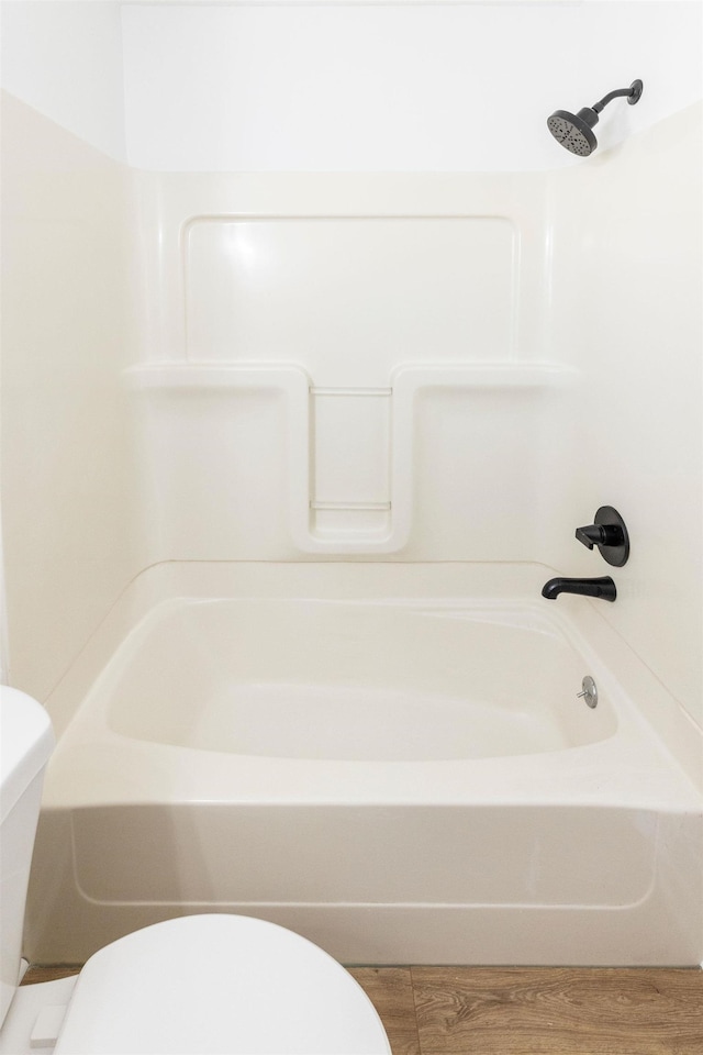 bathroom featuring bathtub / shower combination, hardwood / wood-style floors, and toilet