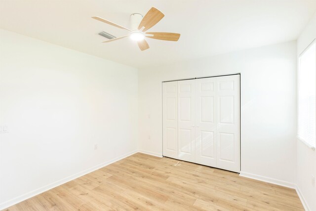 unfurnished bedroom with ceiling fan, a closet, and light wood-type flooring