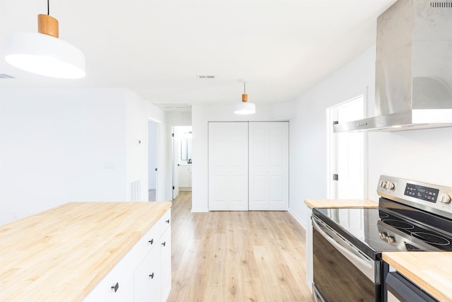 kitchen with stainless steel range with electric cooktop, range hood, hanging light fixtures, and white cabinets