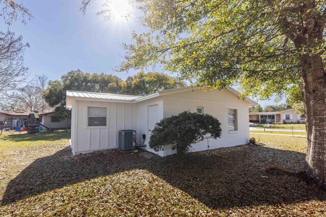 202 Deltona Blvd, Saint Augustine, FL 32086 - view of property exterior featuring board and batten siding, central AC unit, metal roof, and a playground