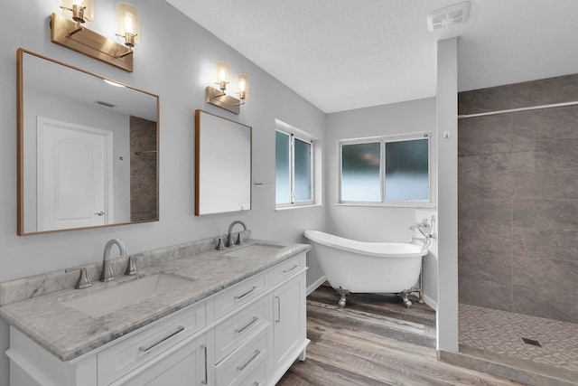 61 Brownstone Ln, Palm Coast, FL 32137 - bathroom featuring wood finished floors, tiled shower, a freestanding tub, and double vanity