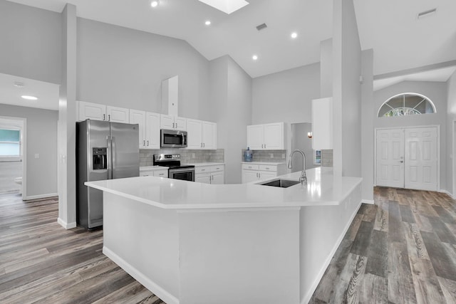 61 Brownstone Ln, Palm Coast, FL 32137 - kitchen featuring stainless steel appliances, high vaulted ceiling, white cabinets, wood finished floors, and tasteful backsplash