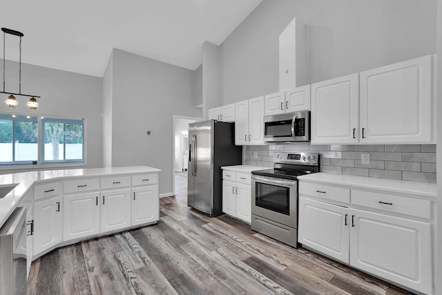 61 Brownstone Ln, Palm Coast, FL 32137 - kitchen featuring stainless steel appliances, high vaulted ceiling, tasteful backsplash, light countertops, and decorative light fixtures