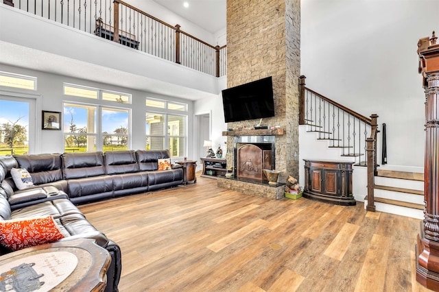 living room with wood-type flooring, a towering ceiling, and a fireplace