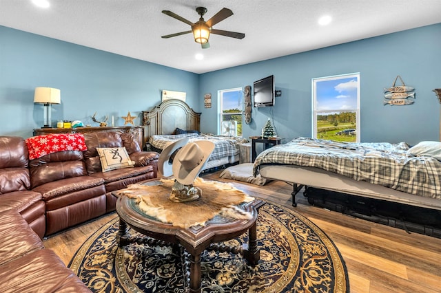 bedroom featuring ceiling fan, light hardwood / wood-style flooring, and a textured ceiling