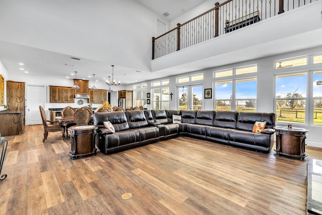 living room with a towering ceiling, light hardwood / wood-style floors, and an inviting chandelier