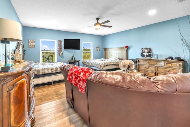 bedroom featuring ceiling fan, light hardwood / wood-style flooring, and a textured ceiling