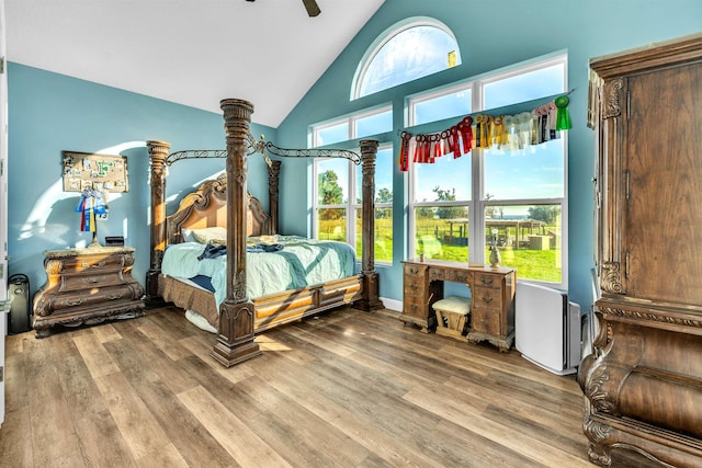 bedroom with hardwood / wood-style floors, ceiling fan, high vaulted ceiling, and multiple windows