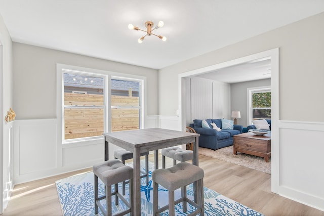 112 2nd St, Saint Augustine, FL 32080 - dining space with a wainscoted wall, a chandelier, light wood finished floors, and a decorative wall