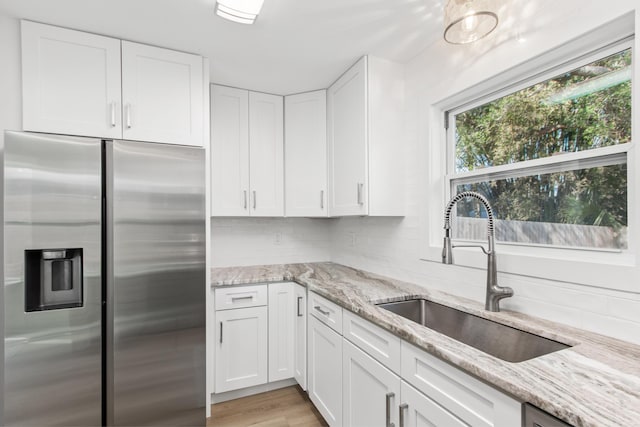 112 2nd St, Saint Augustine, FL 32080 - kitchen with stainless steel fridge, a sink, white cabinetry, and light stone counters