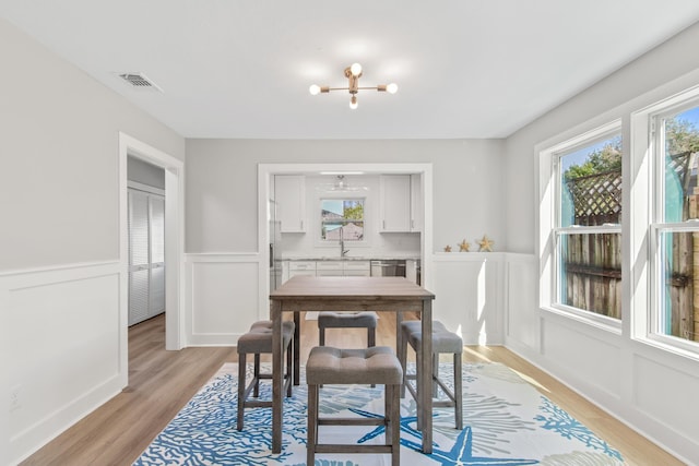112 2nd St, Saint Augustine, FL 32080 - dining area with plenty of natural light, light wood-style flooring, wainscoting, and a decorative wall