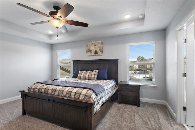 bedroom featuring carpet, a raised ceiling, and baseboards