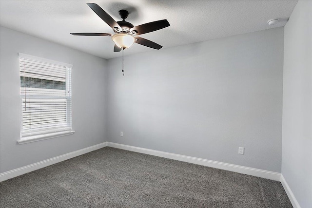 empty room with dark colored carpet, baseboards, a textured ceiling, and a ceiling fan