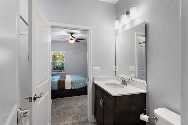 ensuite bathroom with vanity, toilet, a ceiling fan, and connected bathroom