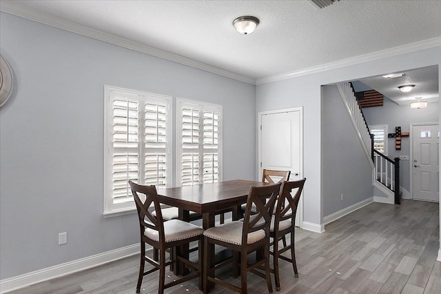 dining area with stairway, baseboards, light wood-style floors, a textured ceiling, and crown molding