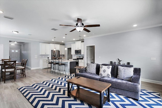 living room featuring baseboards, visible vents, ceiling fan, crown molding, and light wood-type flooring