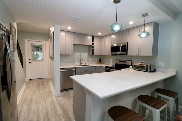 5 N Ocean Palm Villas Unit 5, Flagler Beach, FL 32136 - kitchen featuring stainless steel appliances, a sink, gray cabinets, a peninsula, and light wood-style flooring