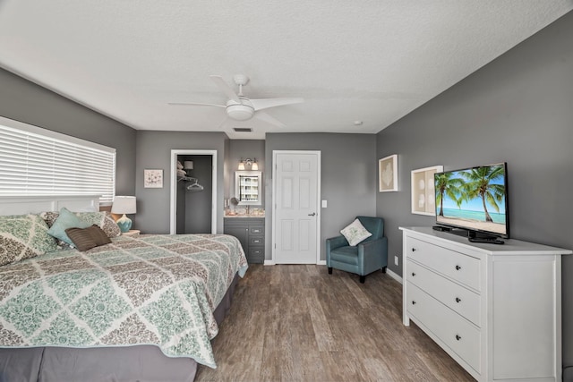 bedroom with ceiling fan, ensuite bathroom, hardwood / wood-style floors, a textured ceiling, and a closet