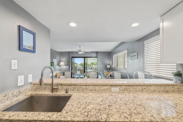 kitchen featuring light stone countertops, sink, and a textured ceiling