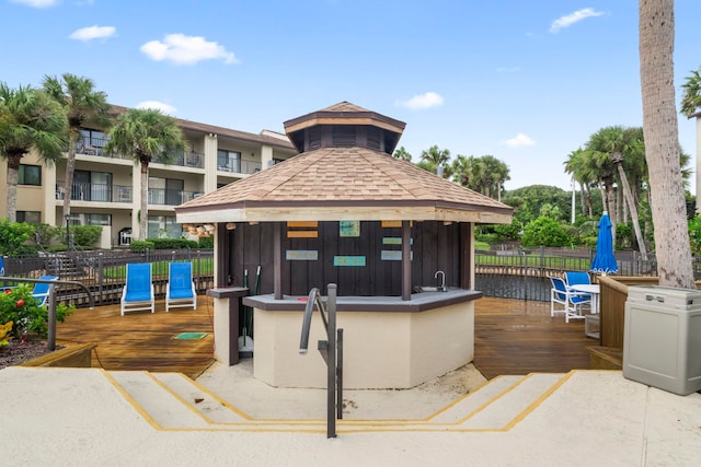 surrounding community with a gazebo, a bar, and a deck