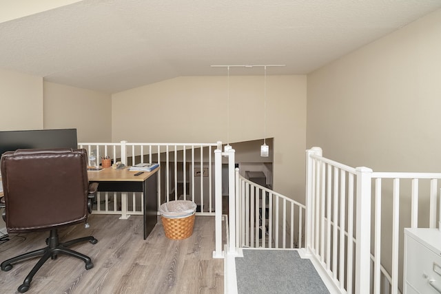 office featuring hardwood / wood-style flooring, track lighting, lofted ceiling, and a textured ceiling