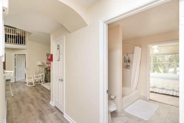 bathroom with shower / bath combination with curtain, ceiling fan, and toilet