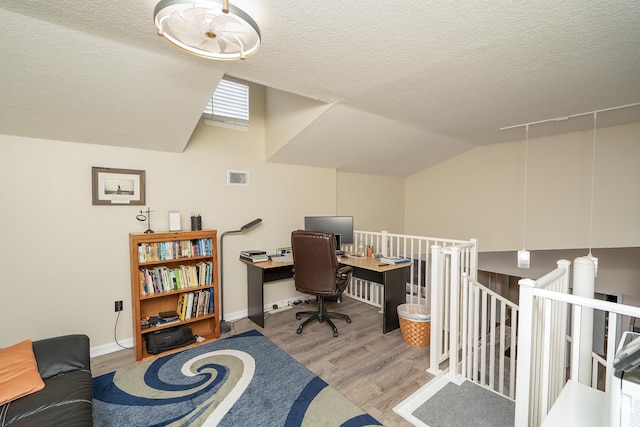 office with vaulted ceiling, a textured ceiling, and light hardwood / wood-style floors