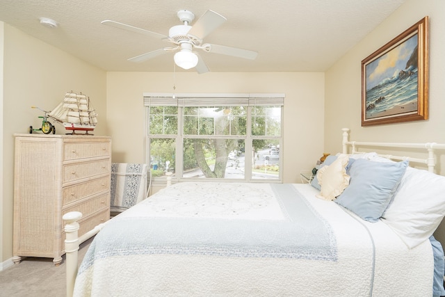 carpeted bedroom featuring ceiling fan and a textured ceiling