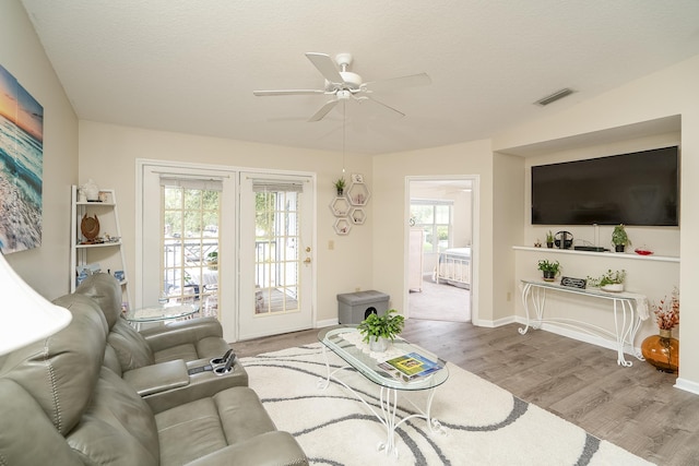 living room featuring hardwood / wood-style flooring, a textured ceiling, and ceiling fan