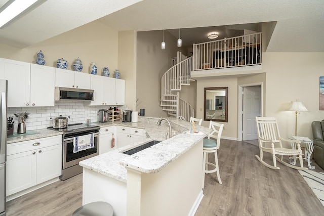 kitchen with a breakfast bar, sink, white cabinets, backsplash, and stainless steel appliances