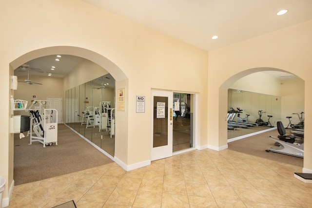 exercise room with french doors, ceiling fan, light tile patterned floors, and a towering ceiling