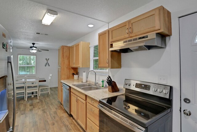 237 Riberia St, Saint Augustine, FL 32084 - kitchen with a textured ceiling, a sink, under cabinet range hood, stainless steel appliances, and light wood-style flooring