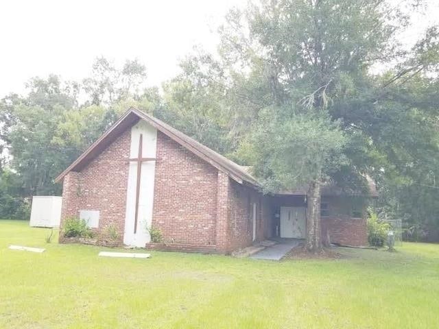 303 E Carter St, Hastings, FL 32145 - view of property exterior featuring a lawn and brick siding