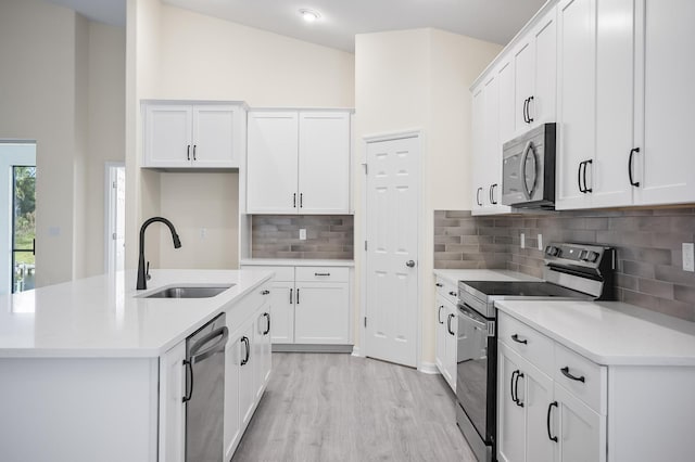 kitchen with stainless steel appliances, vaulted ceiling, white cabinetry, and sink