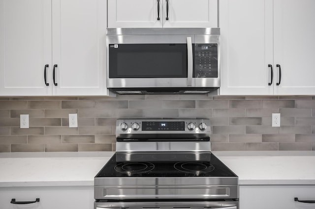 kitchen featuring decorative backsplash, white cabinets, and stainless steel appliances