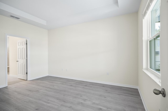 unfurnished room featuring a raised ceiling and light hardwood / wood-style flooring