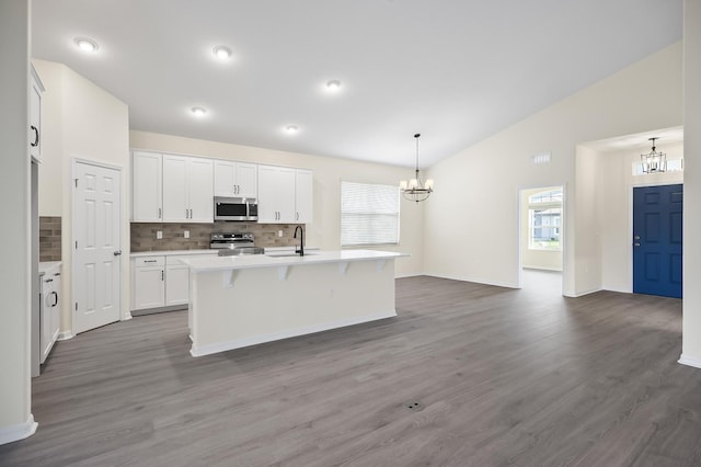 kitchen featuring white cabinets, appliances with stainless steel finishes, dark wood-type flooring, and an island with sink