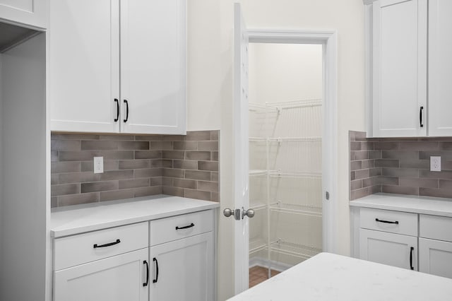 kitchen featuring white cabinets, decorative backsplash, and light stone countertops